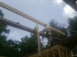 Carpenter setting a ridge beam over a new addition frame — Ice Dam Removal by Roofing Brothers in Roslindale