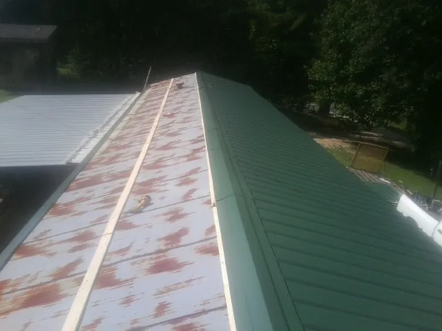 Old rusted panels beside newly installed green metal roofing — Wind Damage Roof Repair by Roofing Brothers in Roslindale