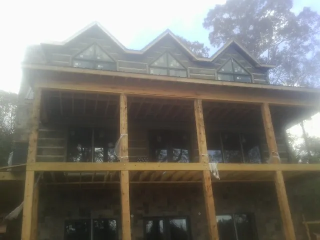 Dormers and porch framing on a large log home under construction — Roof Coating work by our crew in Roslindale