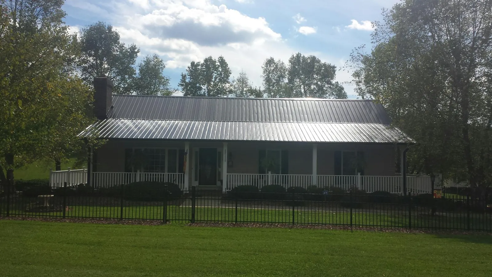 Gray metal roof on a brick ranch with a full width front porch — Gutter Guard Installation work by our crew in Roslindale