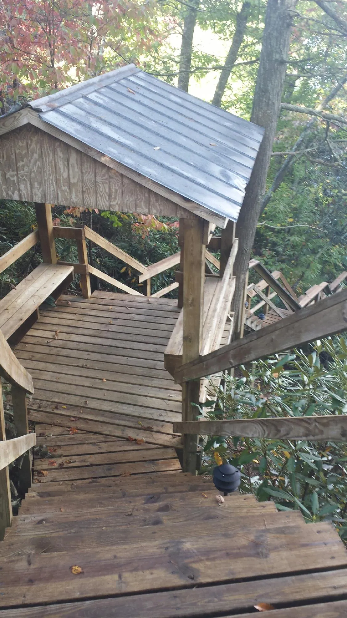 Metal roofed shelter over wooden steps on a wooded walkway — Skylight Repair & Installation work by our crew in Roslindale