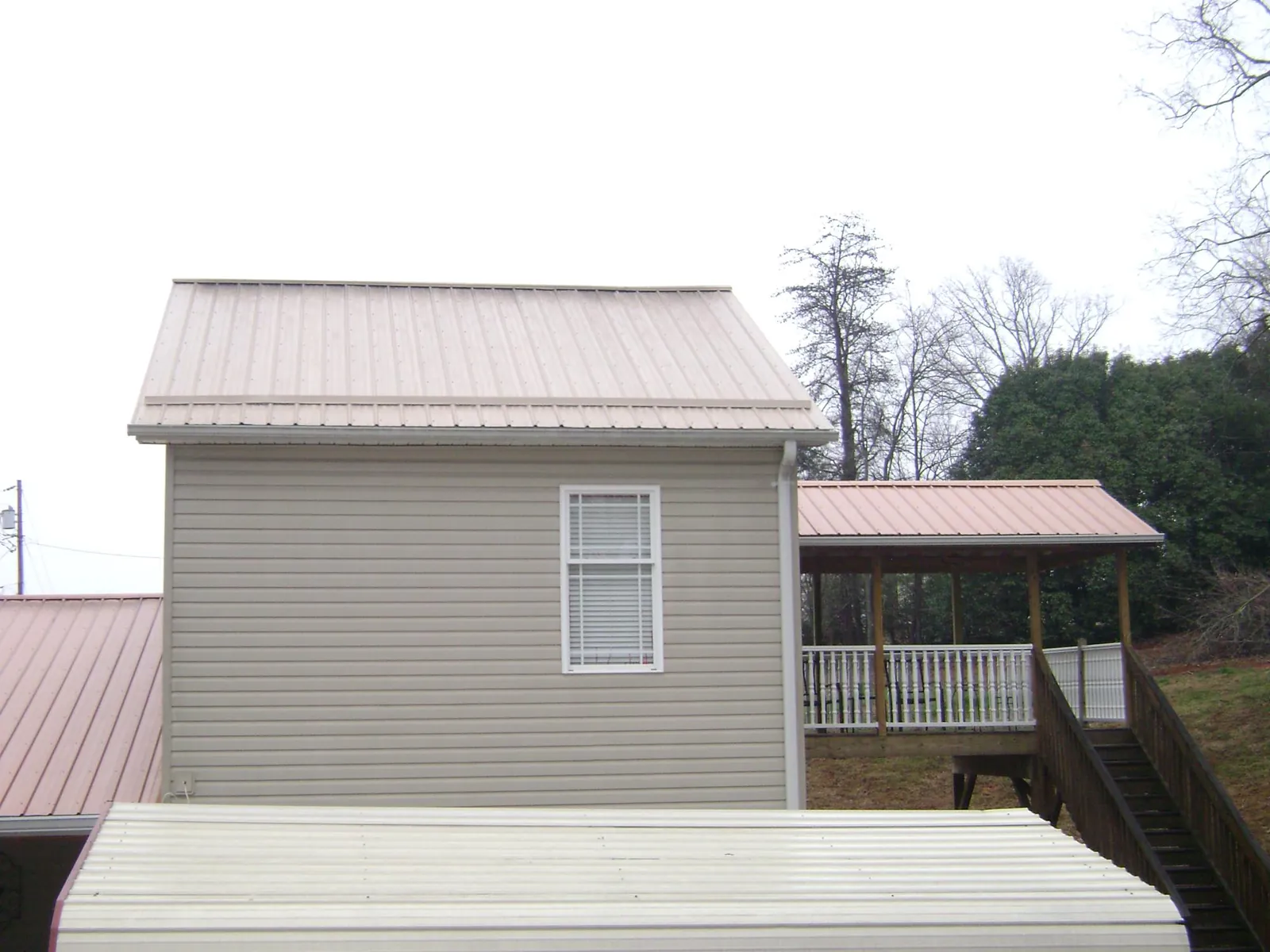 Tan metal roofs on a two story addition and attached porch, from a Roof Replacement job in Roslindale