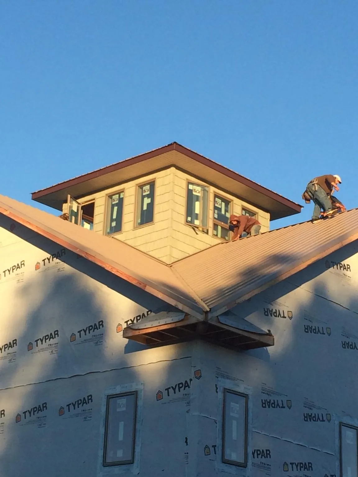 Roofers working around a rooftop cupola on a new metal roof at sunset — Roof Waterproofing in Roslindale by Roofing Brothers
